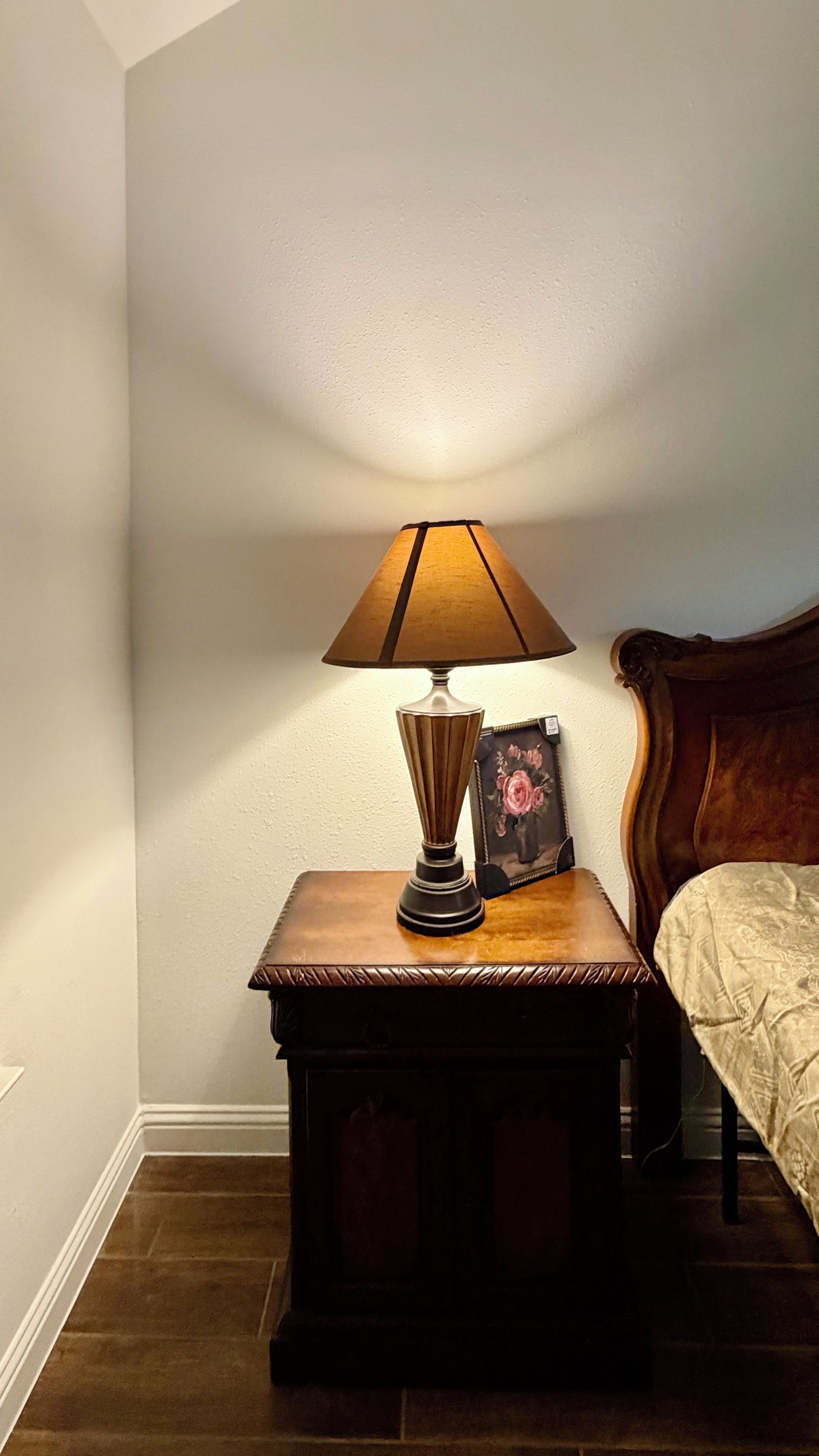 Uma mesa de cabeceira com uma luminária e um quadro emoldurado.