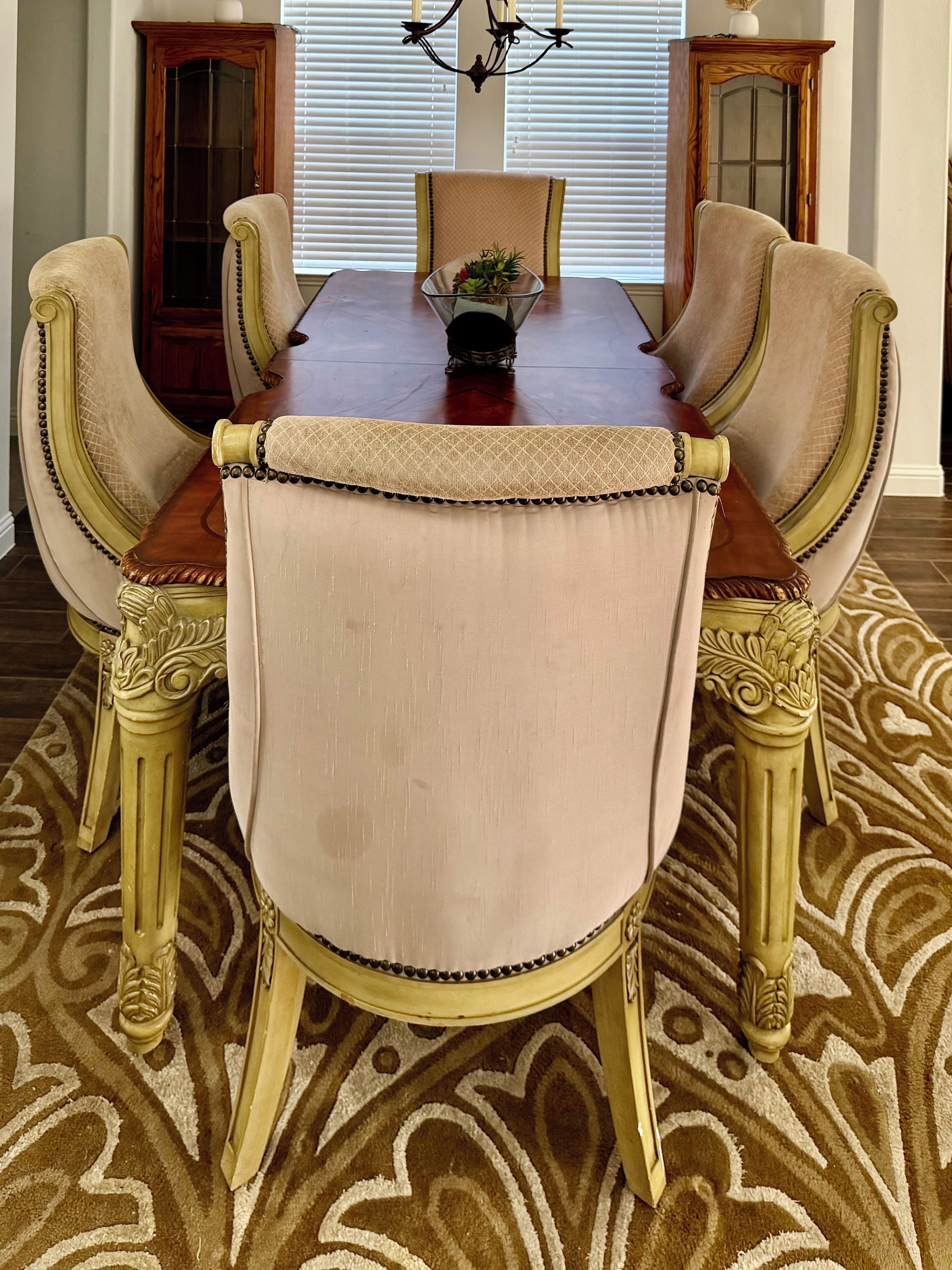 Une salle à manger avec une table en bois, des chaises rembourrées et un tapis à motifs.