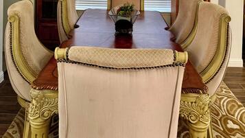 Une salle à manger avec une table en bois, des chaises rembourrées et un tapis à motifs.