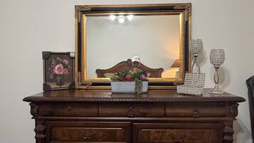 Een houten dressoir met een grote spiegel, een lijst met een afbeelding en decoratieve objecten.