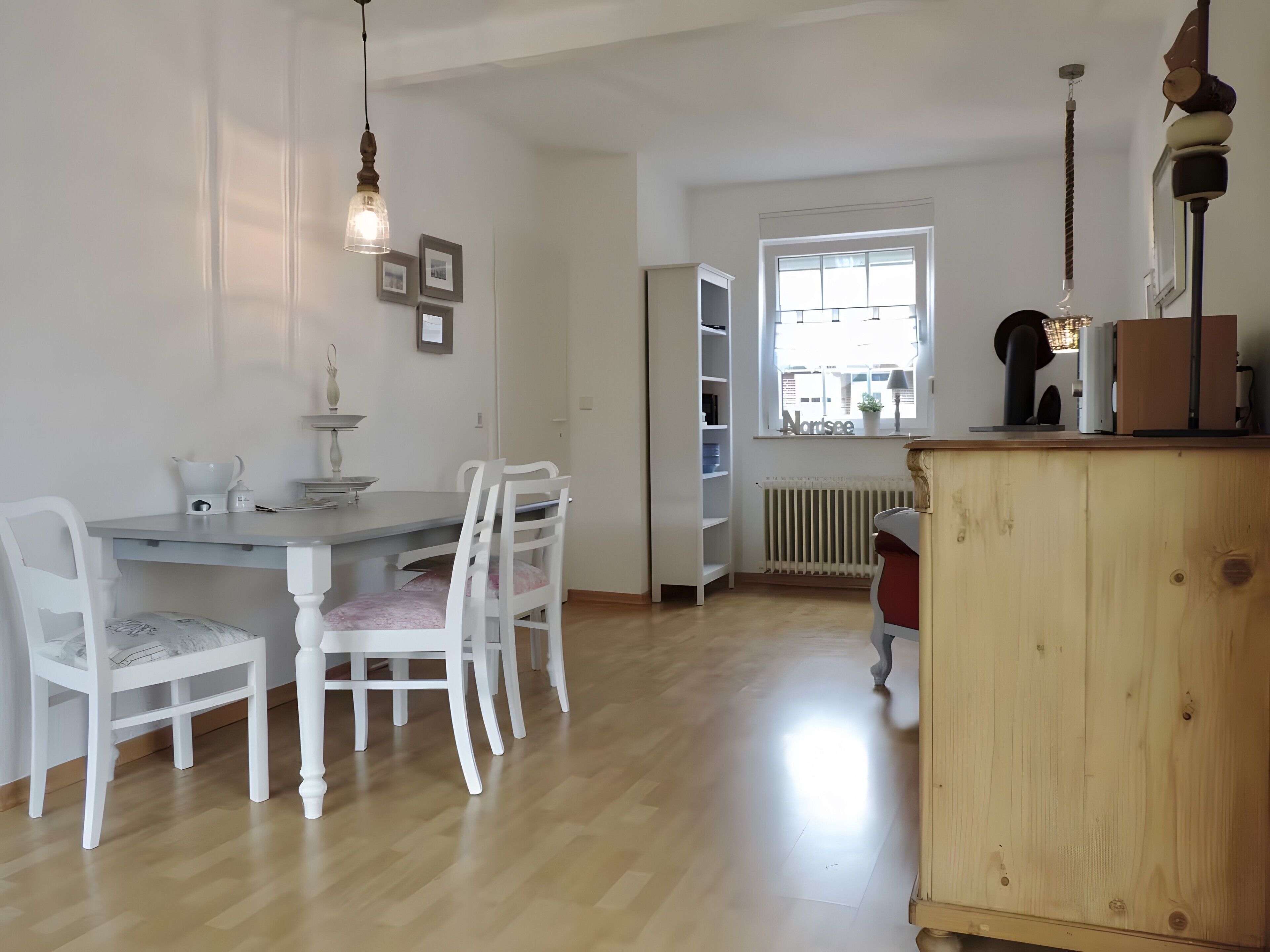 A dining area with a table, chairs, and a wooden cabinet.