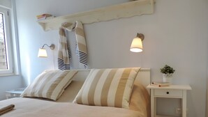 En pænt redt seng med stribede puder, et natbord med en lampe og en lille plante på sengebordet.