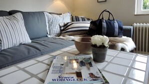 En moderne stue med en sofa, et sofabord med et magasin, en potteplante og en radiator.