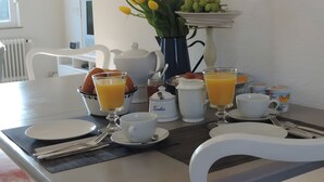 A breakfast table set with plates, cups, and a vase of flowers.