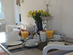 A breakfast table set with plates, cups, and a vase of flowers. - Holiday Home 'Dat Luettje Huus' with Private Terrace and Garden (Hage)