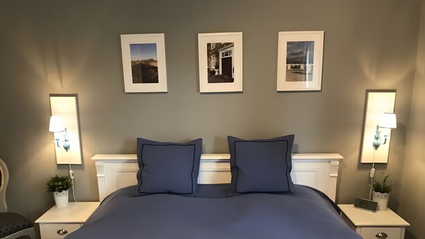 Una camera d'albergo con un letto grande, due comodini con lampade e tre quadri appesi al muro.