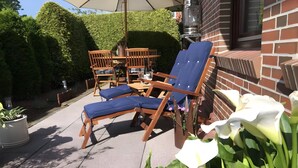 Un patio esterno con poltrone relax, un tavolo e una pianta in vaso.