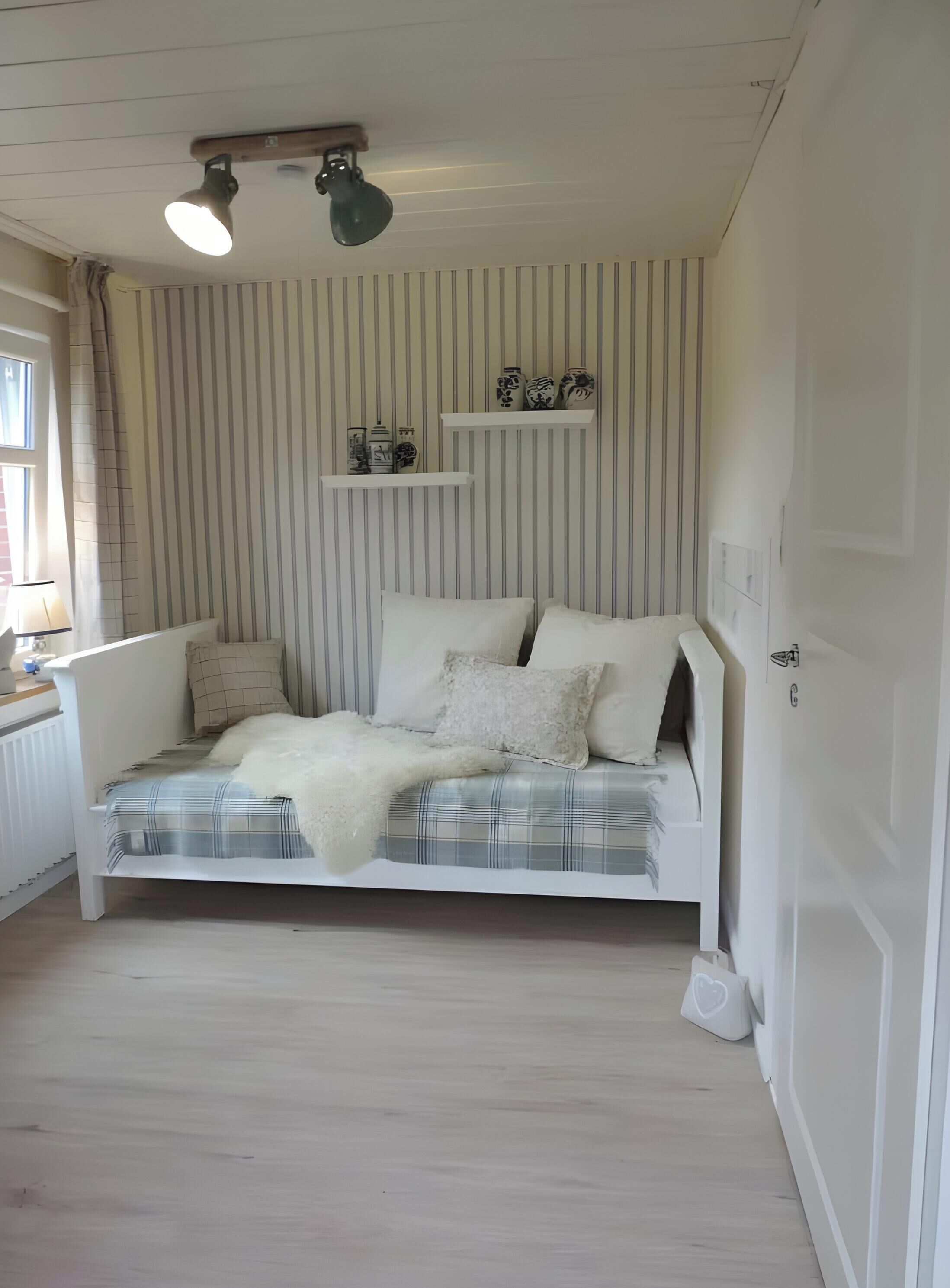 A room with a bed, a window with curtains, a radiator, and a ceiling light fixture.