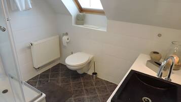 Ein modernes Badezimmer mit Oberlicht, Toilette, Waschbecken und Duschbereich.