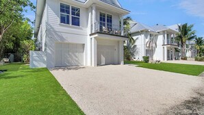 A two-story house with a covered garage, a balcony, and a well-maintained lawn. - Captain's Quarters Longboat Key (Longboat Key)
