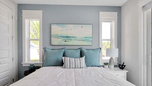 A bedroom with a bed, two windows, a nightstand, a lamp, and a painting. - Captain's Quarters Longboat Key (Longboat Key)