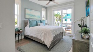 A bedroom with a bed, a ceiling fan, a painting, and a view of the outside. - Captain's Quarters Longboat Key (Longboat Key)