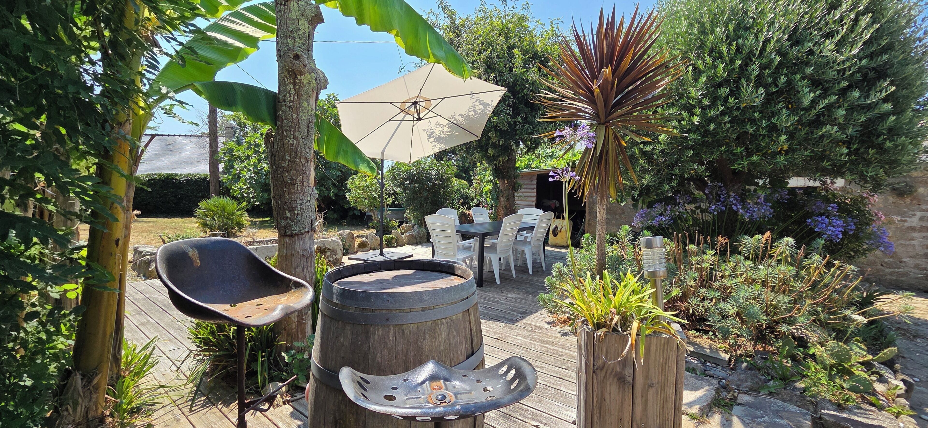 A wooden deck with outdoor furniture, a barbecue grill, and a large umbrella.