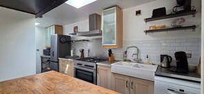 A modern kitchen with a stove, oven, sink, and a wooden dining table.