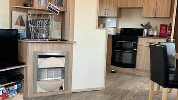 A compact kitchen with wooden cabinets, a built-in oven, and a small refrigerator.