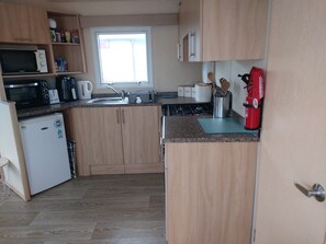 Cocina compacta equipada con microondas, tostadora, hervidor y un refrigerador pequeño.