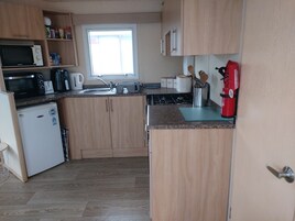 Cocina compacta equipada con microondas, tostadora, hervidor y un refrigerador pequeño.