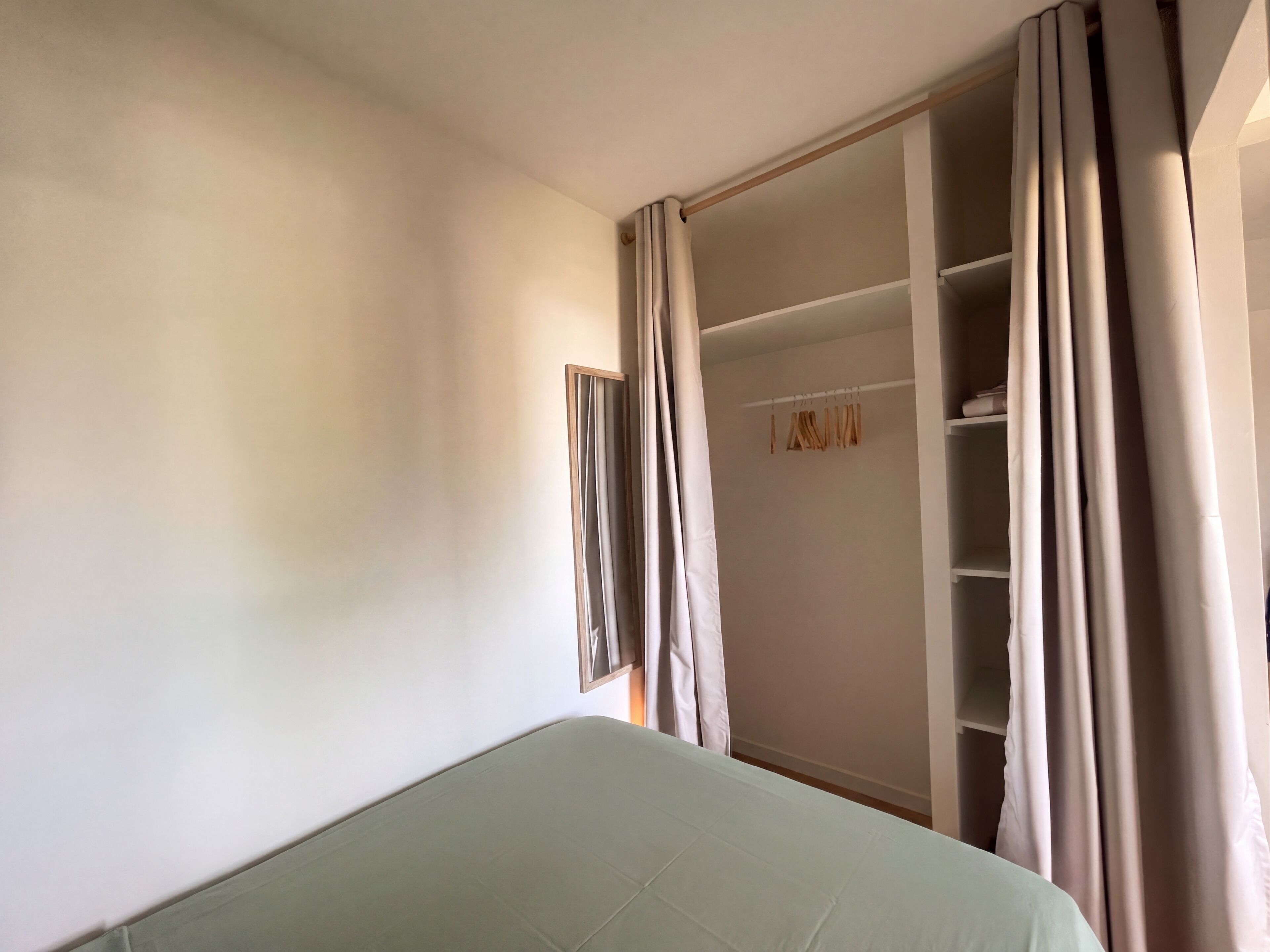 A room with a bed, a wardrobe, and a mirror.