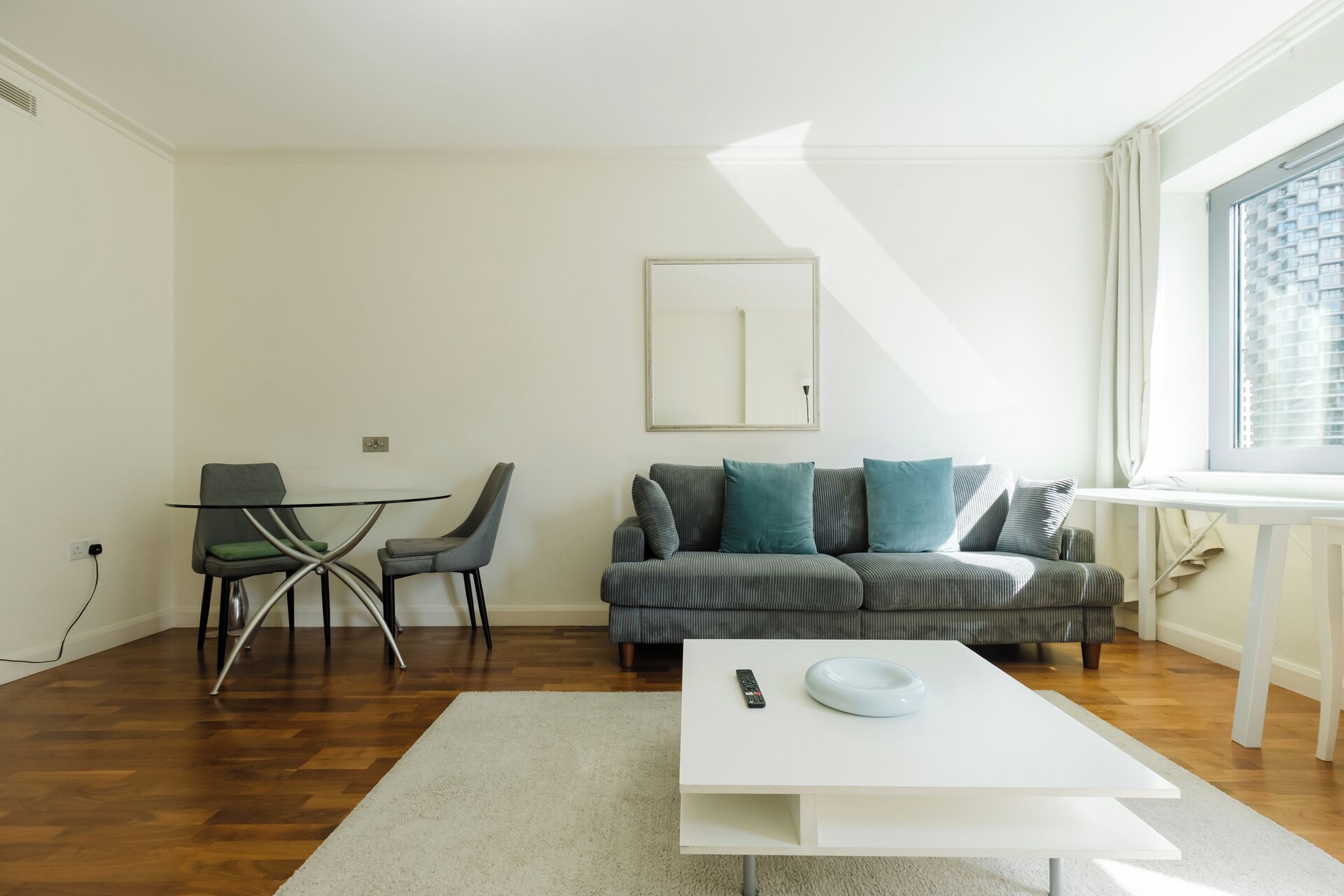 Una sala de estar moderna con un sofá, una mesa de centro y un comedor con sillas.