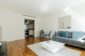 Ein modernes Wohnzimmer mit Sofa, Couchtisch und Essbereich mit Stühlen.