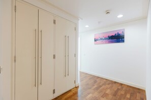 A hallway with wooden flooring, white walls, and a cityscape painting. - Sleek 1BDR City Stay In Canary Wharf (Greater London)