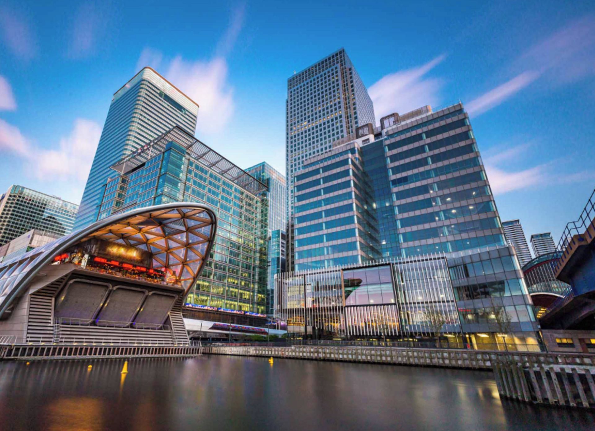 A modern cityscape with high-rise buildings and a distinctive curved structure in the foreground.