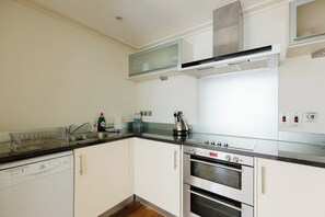 A modern kitchen with stainless steel appliances, including a dishwasher, oven, and kettle. - Sleek 1BDR City Stay In Canary Wharf (Greater London)