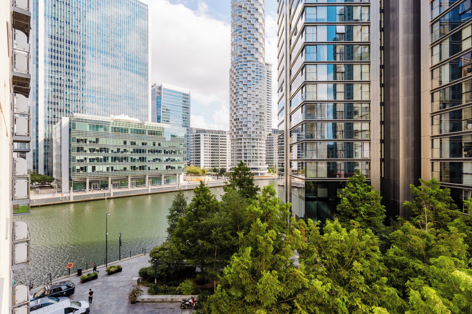 A high-rise urban area with modern architecture, a river, and lush greenery.