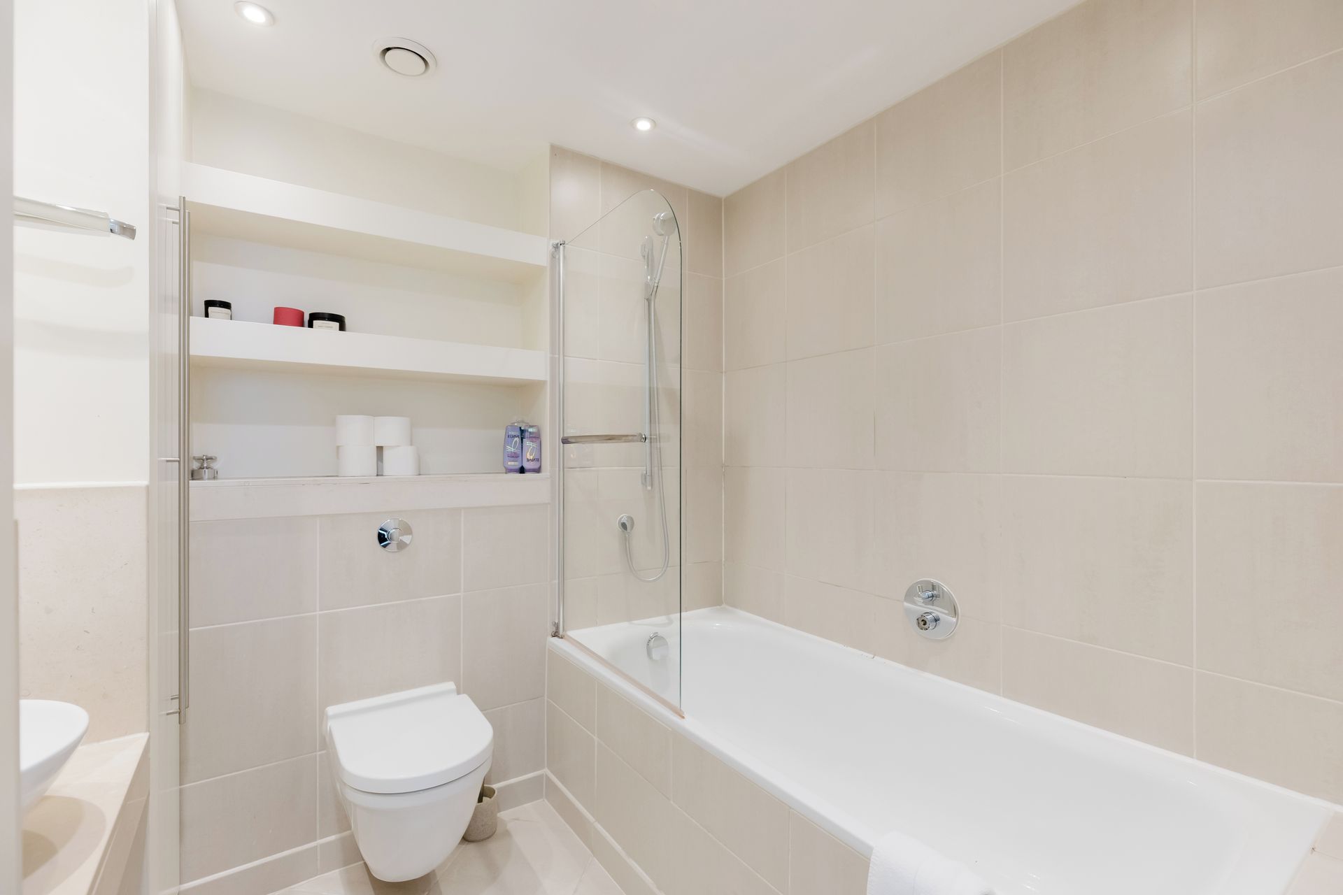 A modern bathroom with a toilet, a glass-enclosed shower, and a bathtub.
