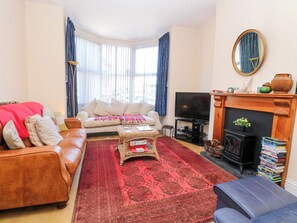 Ein Wohnzimmer mit Sofa, Couchtisch, Fernseher, Kamin und Bücherregal.