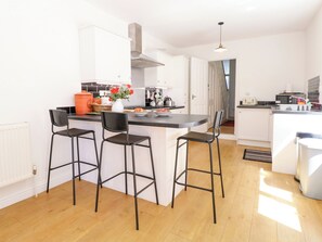 Eine moderne Küche mit einer zentralen Kochinsel, Barhocker und Blick in den Essbereich.
