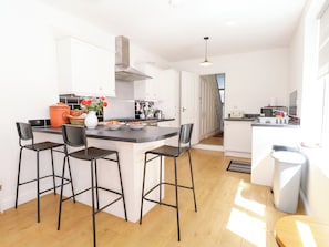 A modern kitchen with a central island, bar stools, and a view to the dining area. - 33 North Denes (Great Yarmouth)
