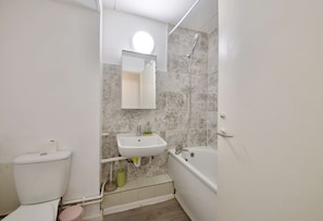Ein Badezimmer mit Toilette, Waschbecken, Spiegel, Dusche und Badewanne.