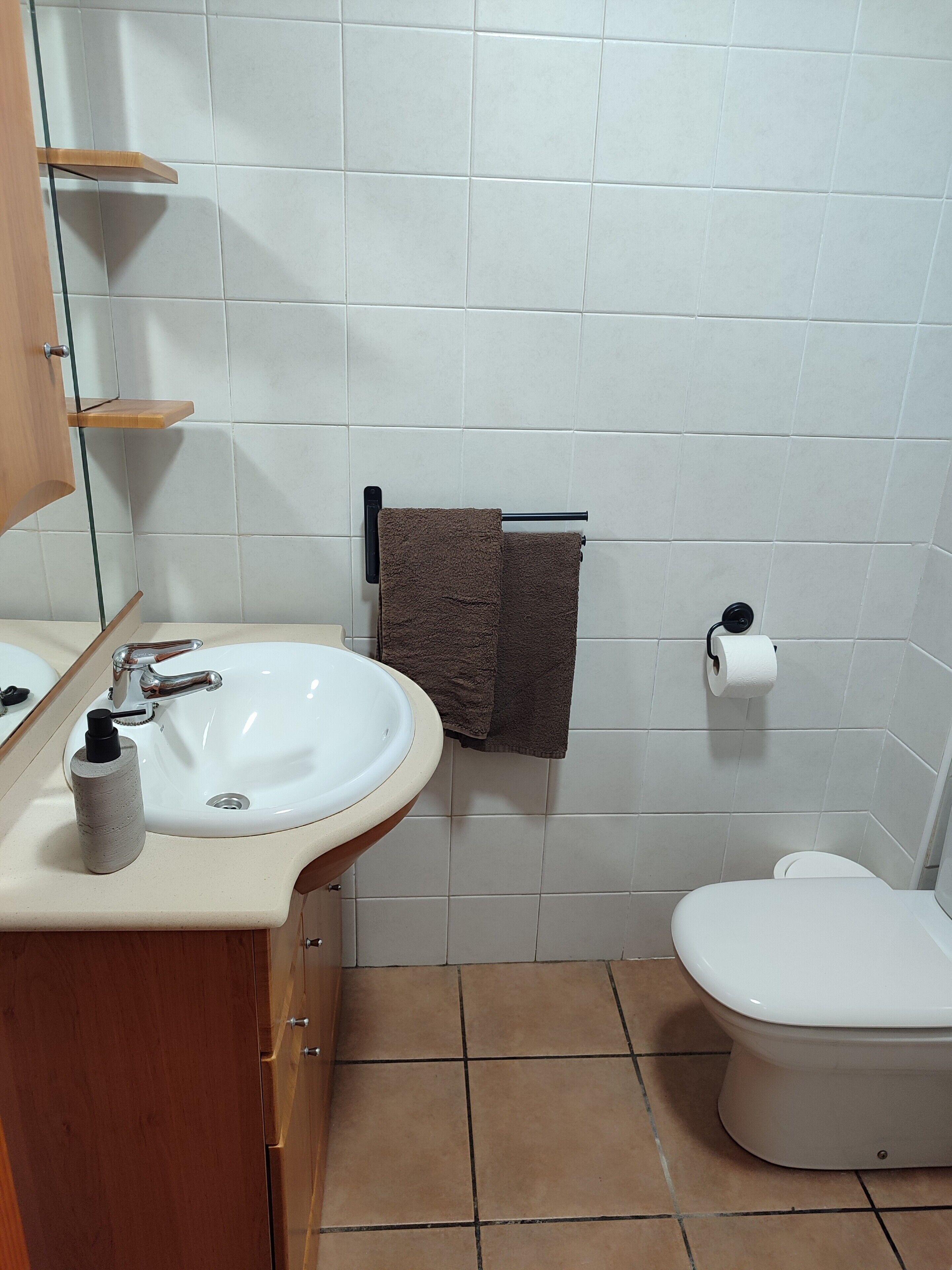 Un baño con lavamanos blanco, inodoro y toallero.
