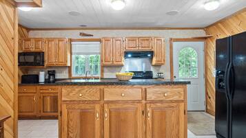A kitchen with wooden cabinets, a black refrigerator, a microwave, and a coffee maker.