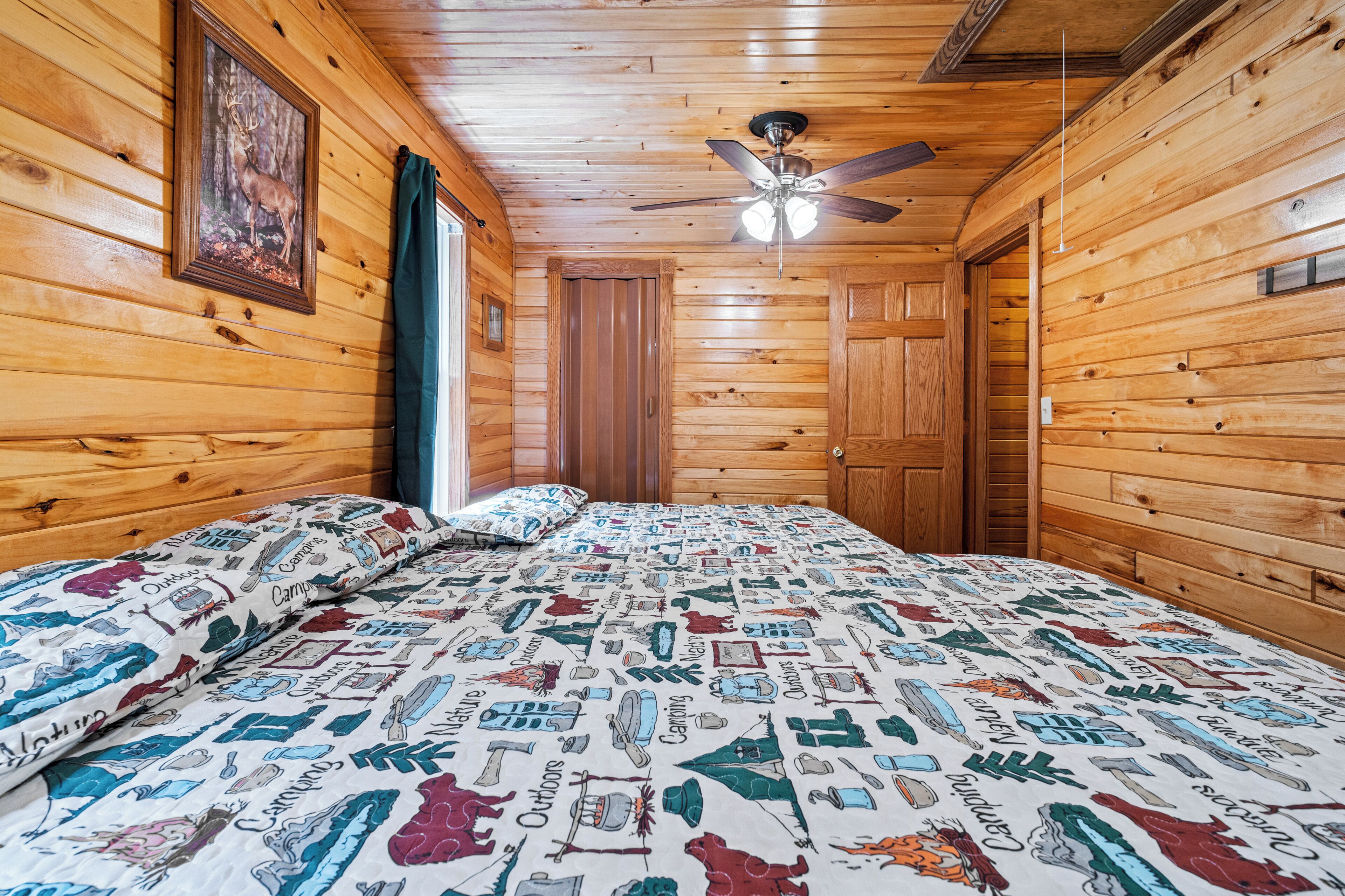 Una habitación de cabaña de madera con una cama, un ventilador de techo y una puerta.