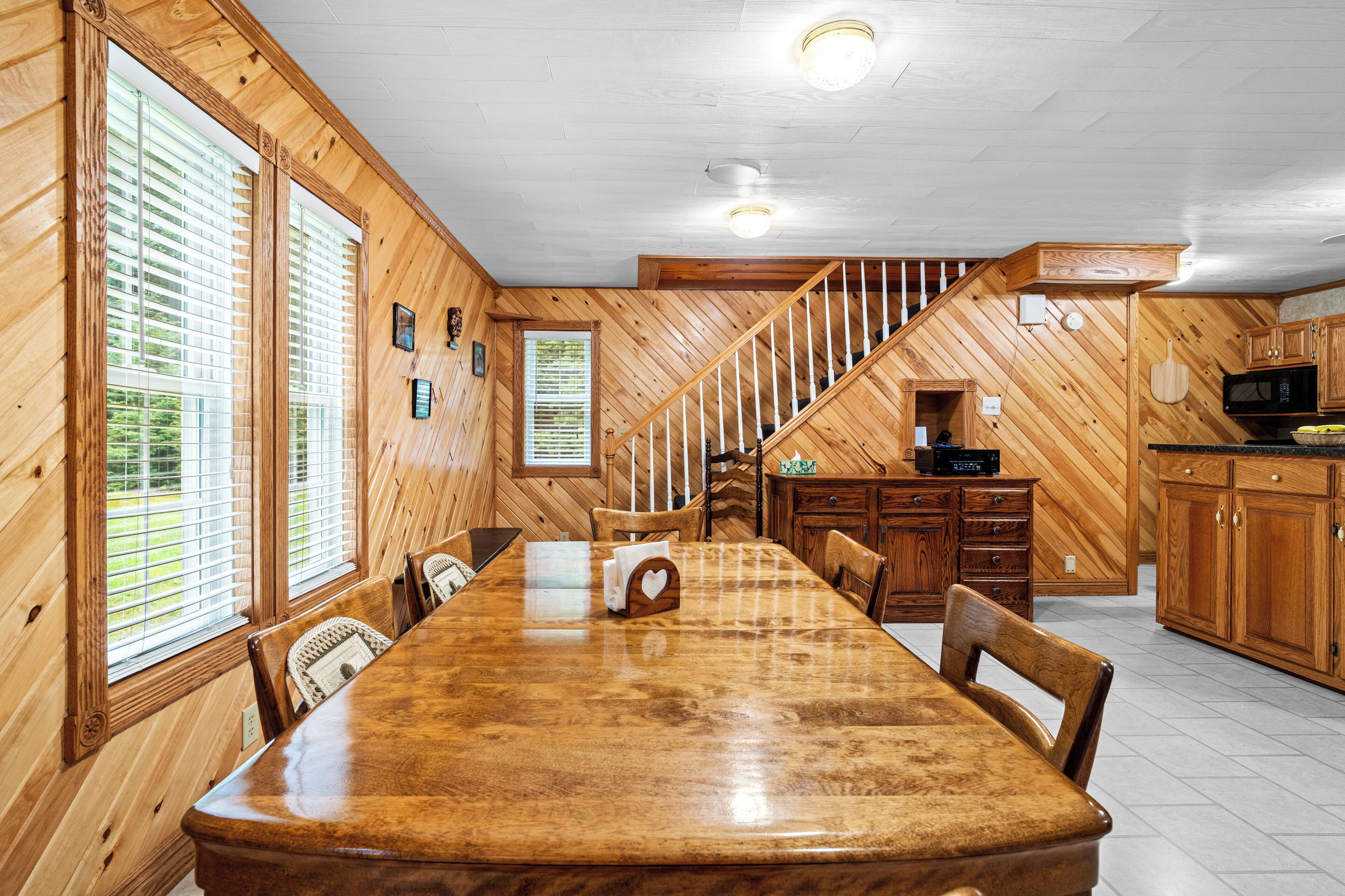 Un intérieur en bois comprenant une table à manger, des chaises, un coin cuisine et un escalier.