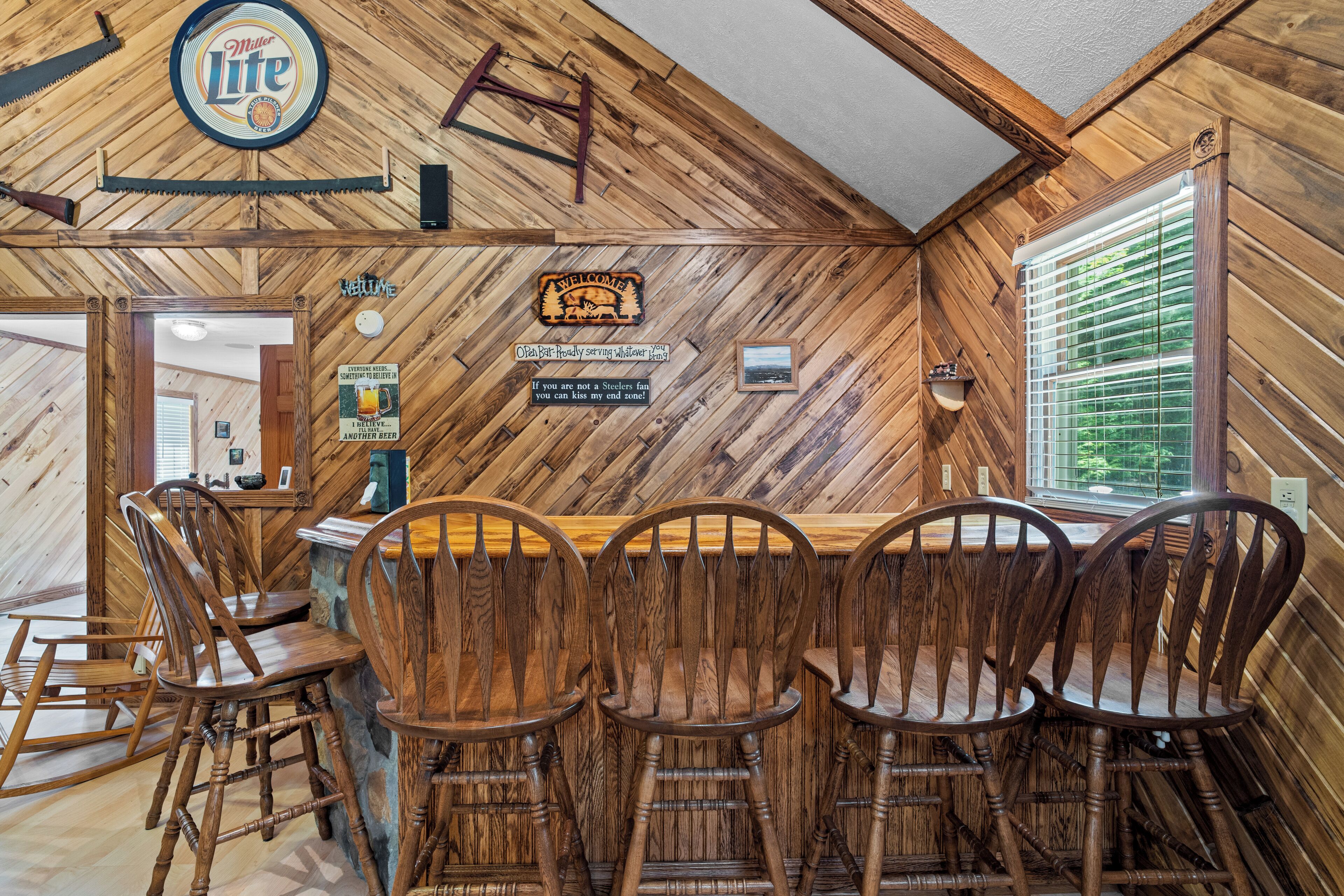 A rustic bar area with wooden walls, a Miller Lite sign, and a welcome sign.
