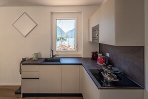 A modern kitchen with a window, a sink, a stove, and cabinets.