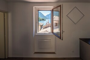 A room with a window overlooking a mountainous landscape and a body of water.