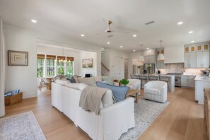 A spacious living area with a sofa, chairs, a dining table, and a kitchen with cabinets and a stove. - NEW! 30A Home! Dock, Golf Cart, Putting Green, Community Pool & 4 Bikes (Santa Rosa Beach)