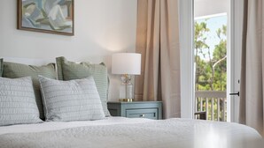 A neatly made bed with pillows, a bedside table with a lamp, and a view of greenery through a window. - NEW! 30A Home! Dock, Golf Cart, Putting Green, Community Pool & 4 Bikes (Santa Rosa Beach)