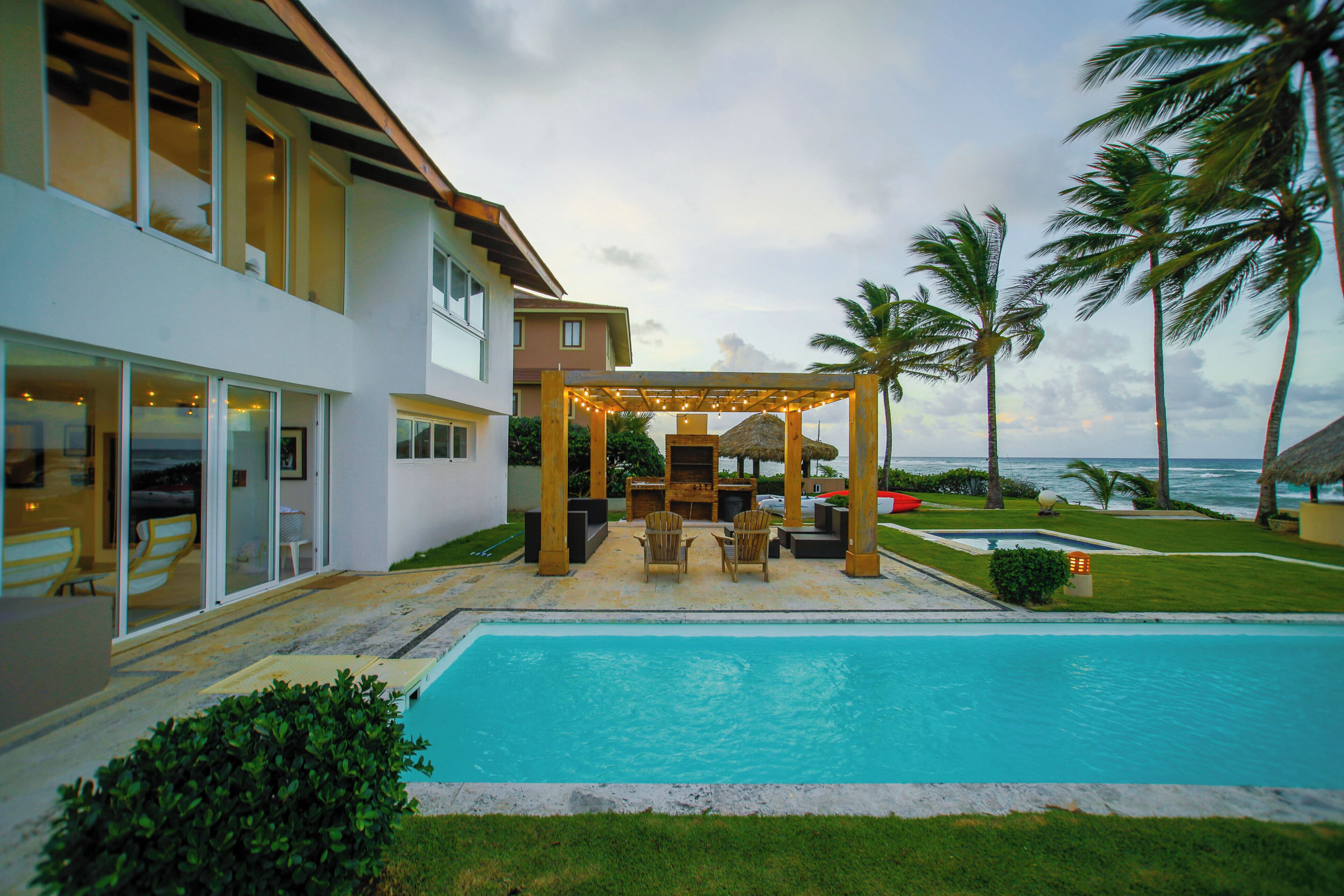 A modern house with a pool, outdoor seating, and a view of the ocean.