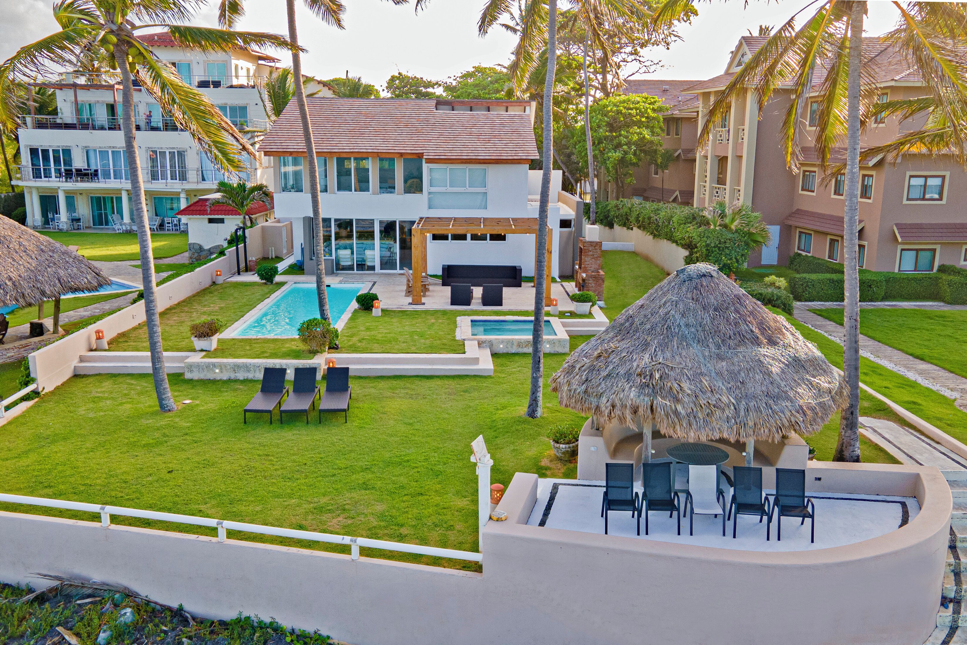Um resort com piscina, área de estar externa e uma construção com telhado de palha.
