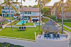 A resort with a pool, outdoor seating, and a thatched-roof structure.