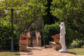 Ein Gartenweg mit einer Statue, Blumentöpfen und einer Steintreppe.