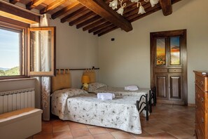 Ein Schlafzimmer mit einem Bett, einem Heizkörper, einer Bank, einem Schminktisch und einem Fenster mit Blick.