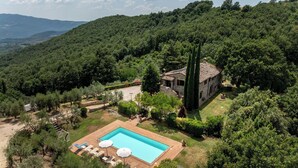 Une villa avec piscine, entourée d’une végétation luxuriante et de collines.