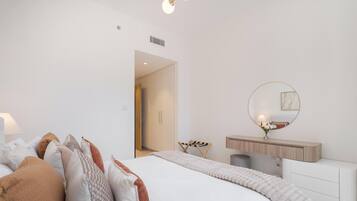 Un dormitorio moderno con cama, mesita de noche, espejo y vistas a otra habitación.