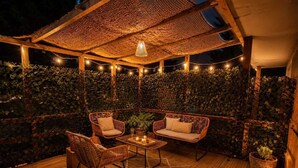 A covered outdoor seating area with wicker furniture, string lights, and a wooden floor. - Appartement avec terrasse privée , parking privé, à 7 min des Thermes de Saujon (Saint-Romain-de-Benet)